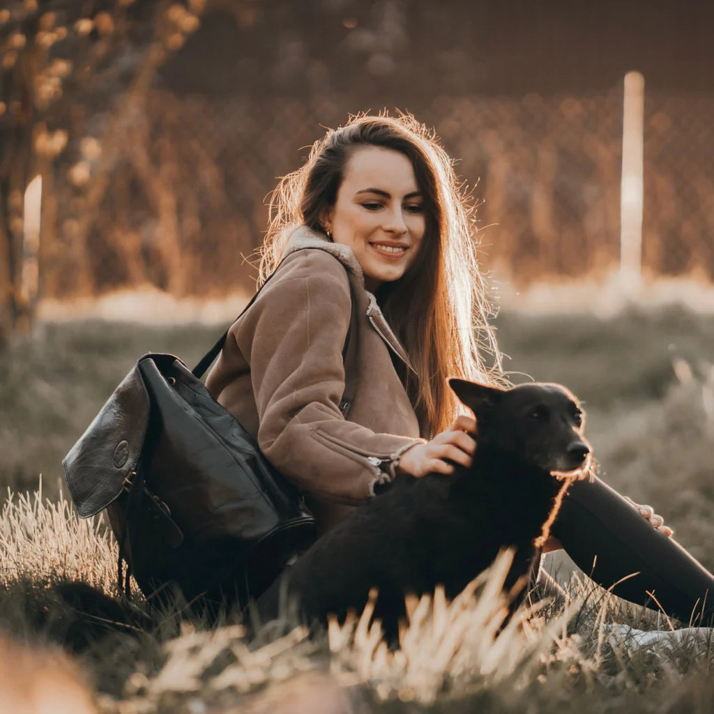 Woman with dog on a field wearing a black backpack vivify. Timeless elegance: Effortlessly stylish, Classic design, Enduring appeal, Time-honored aesthetics, Everlasting beauty.